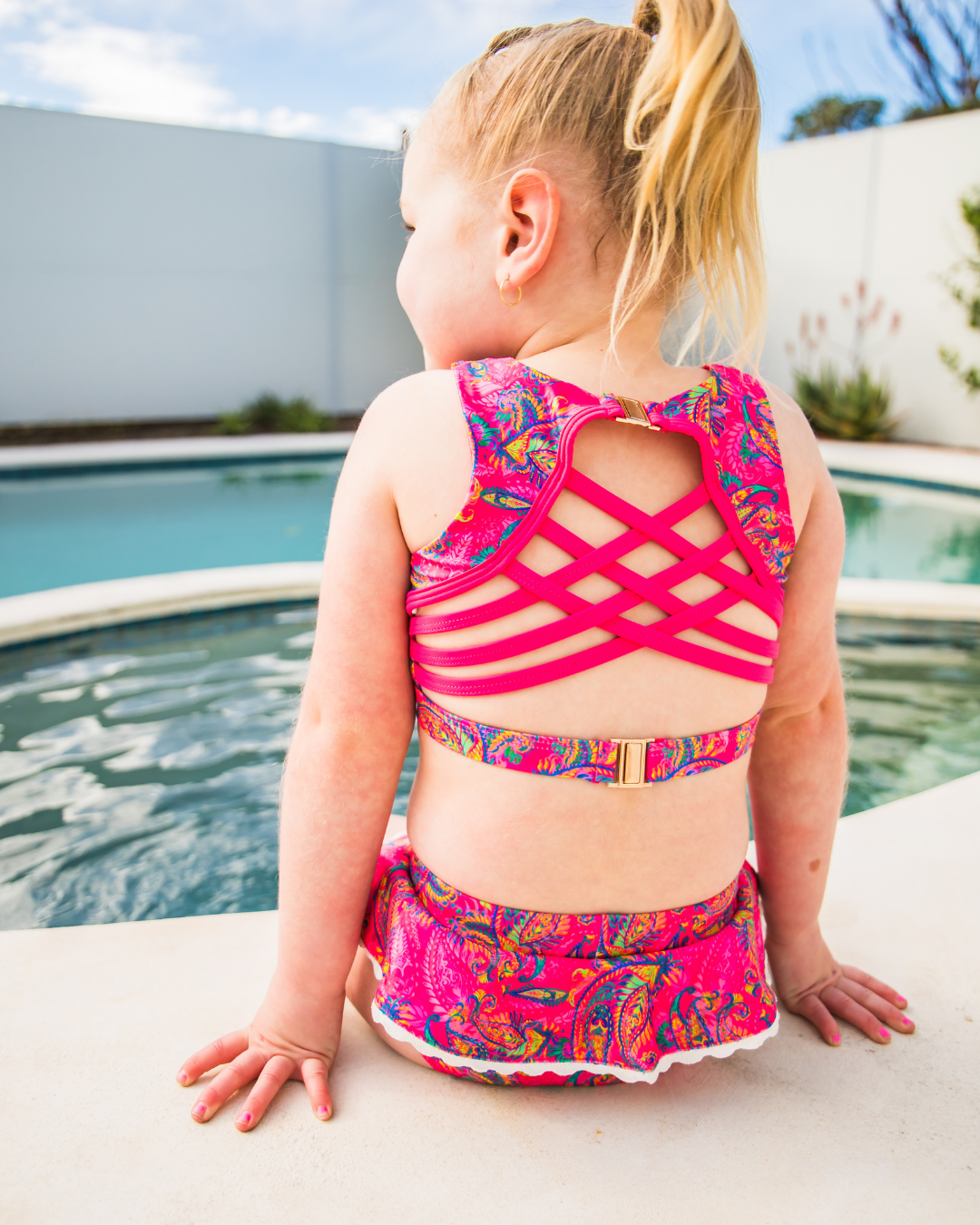 Child wearing a colorful girls swimsuit by a pool