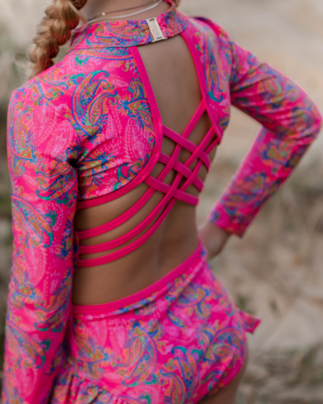 Bright pink and multicolor patterned long-sleeve swimsuit with open back design.