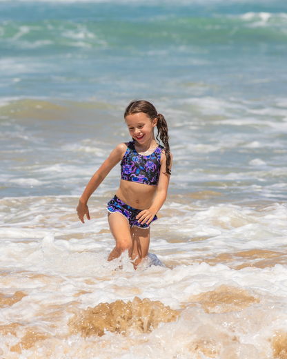 Young girl in a colorful girls swimsuit playing in the ocean waves.