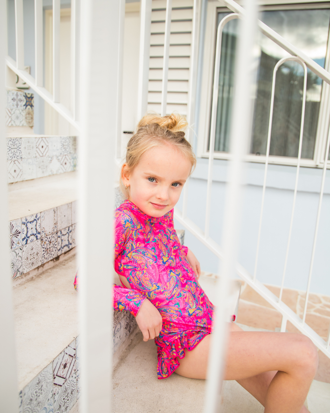 Young girl in a colorful girls swimmers sitting on a staircase.