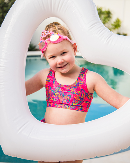 Child in a colorful  girls swimsuit with a pink swim ring in a pool