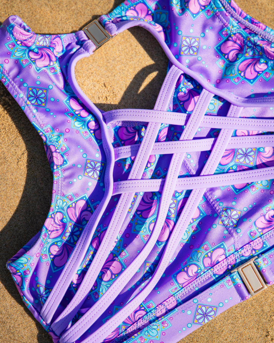 Purple and pink floral swimming costume set on a sandy surface