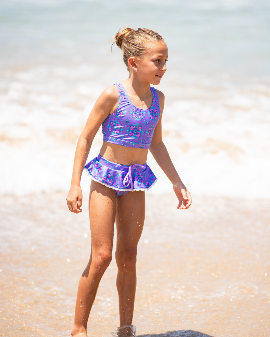 Young girl in a purple girls bathers standing on a beach