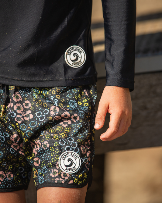 Person wearing boys swimwear including shorts with a brand logo.