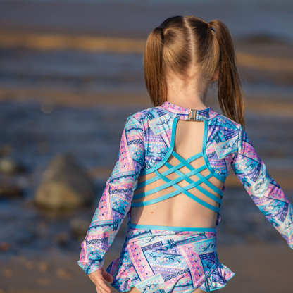 Young girl wearing a colorful girls swimers with a geometric pattern by the water.