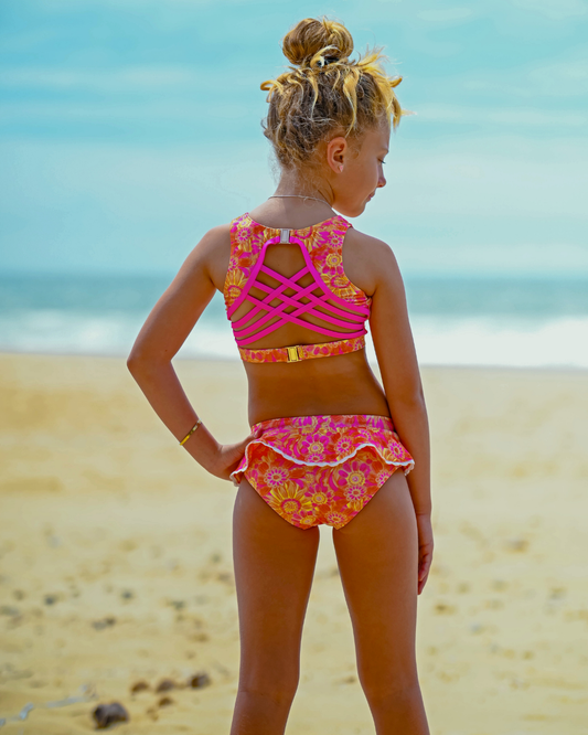 Young girl in a colorful teen swimsuit standing on a beach with ocean view
